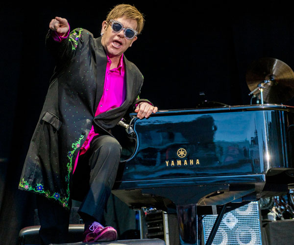 Elton John mit Smoking und Sonnenbrille bei einem Auftritt am Flügel