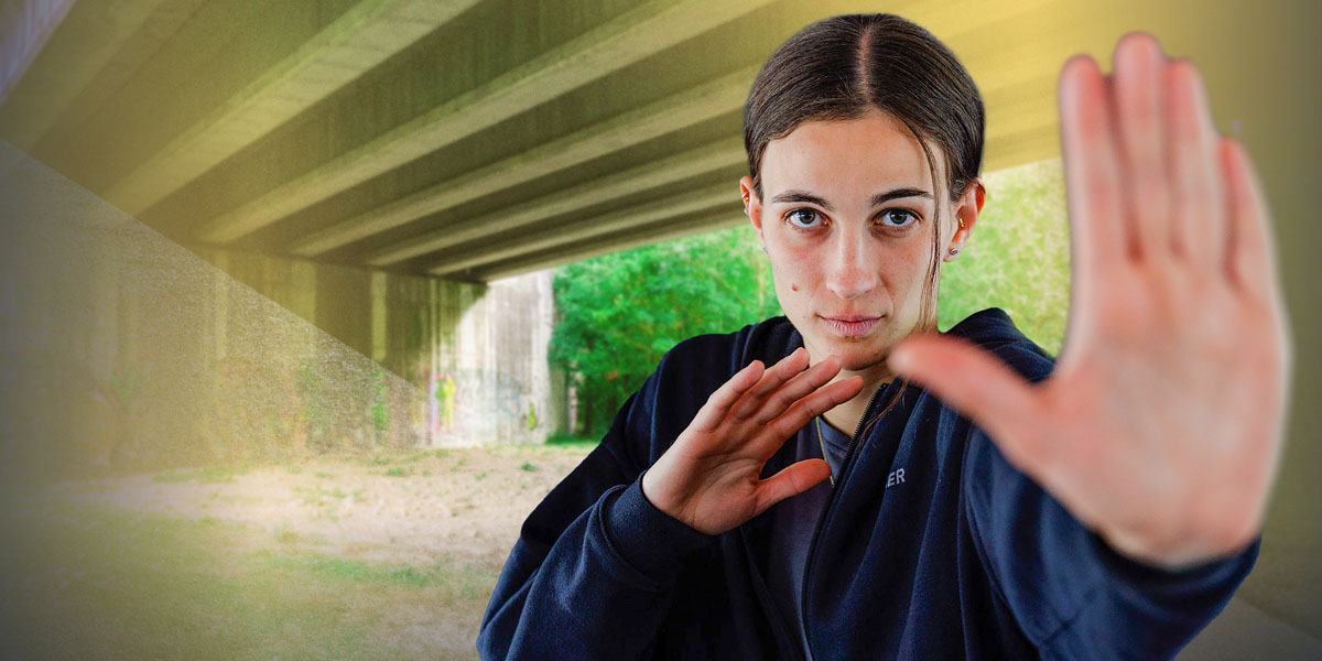 Pia steht in einer Unterführung, macht eine abwehrende Handbewegung