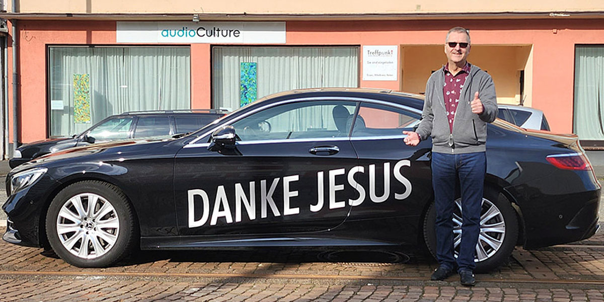 Diethard Kumpf vor einer schwarzen Limousine mit dem Schriftzug "Danke Jesus"
