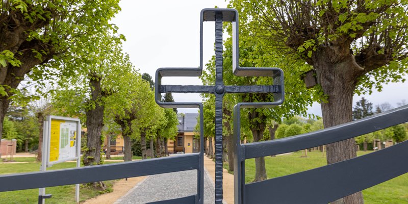 Blick durch ein Tor mit Kreuz auf den Weg in die Gedenkstätte Großschweidnitz