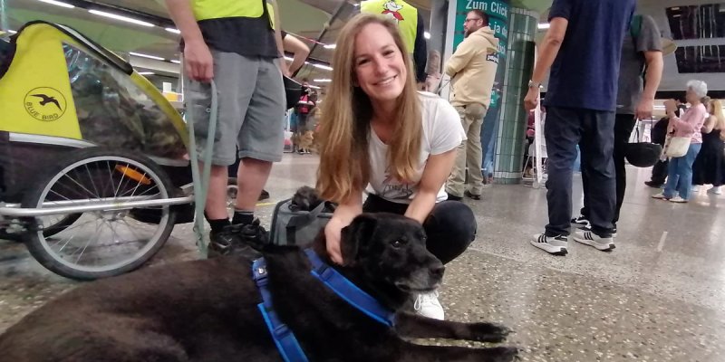 Simone streichelt einen schwarzen Hund am Bahnhofsplatz