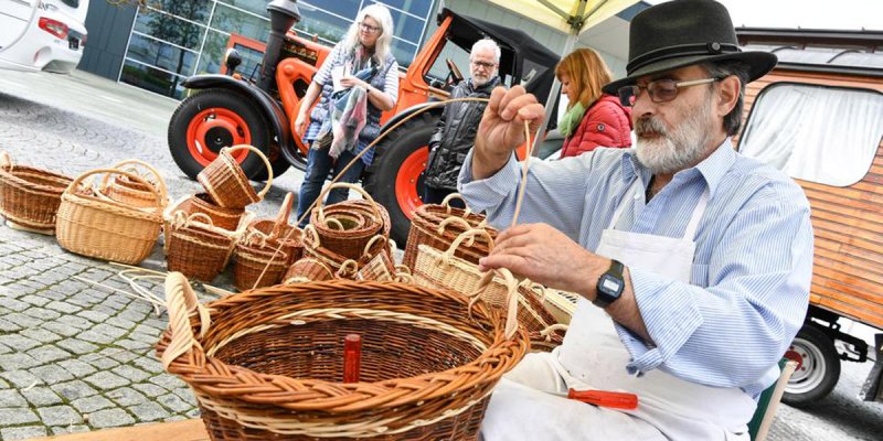 Der Jenische Hans Nobel aus der Schweiz flicht während eines jenischen Kulturfestes einen Korb auf der Straße sitzend.
