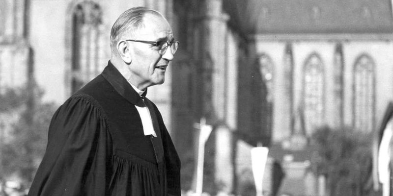 Der Theologe Martin Niemöller in einer schwarz-weißen Aufnahme im Talar vor einer Kirche